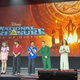 seven people on stage with the poster behind them